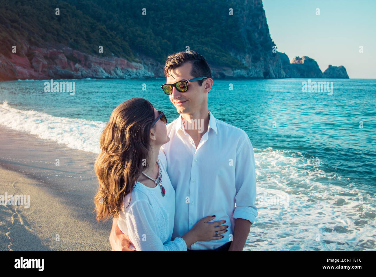 Junge glückliches Paar umarmen am tropischen Strand am Morgen. Ferienhäuser Konzept Stockfoto Junge glückliches Paar umarmen am tropischen Strand am Morgen. Ferienhäuser Konzept Stockfoto