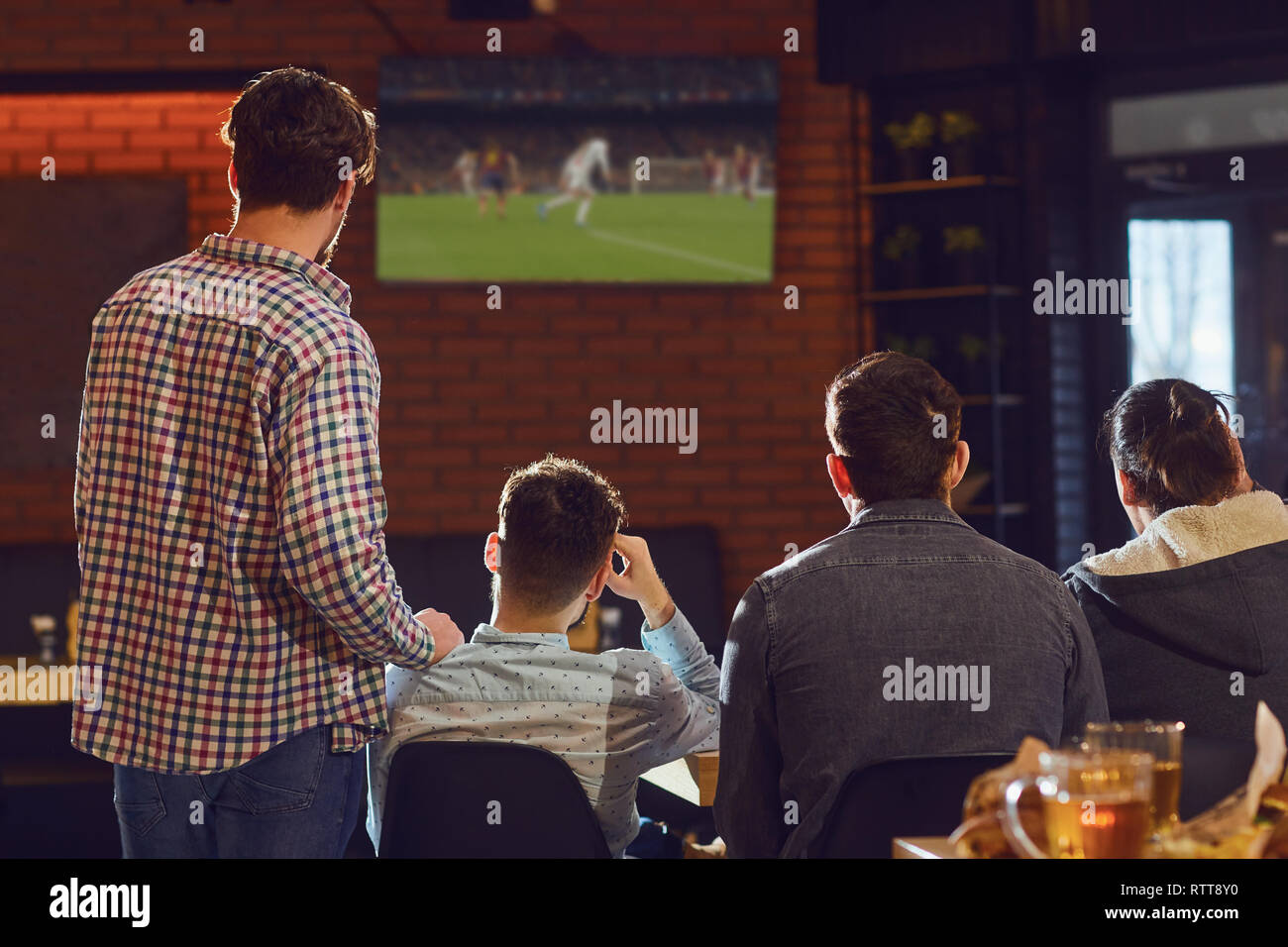 Junge Menschen, Fußball im Fernsehen in der Bar. Stockfoto