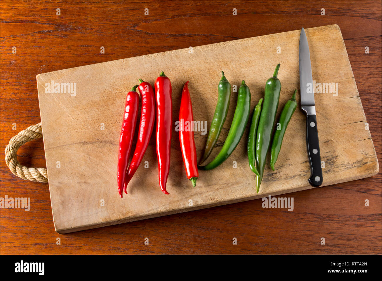 Rot und Grün hot chili peppers auf einem Schneidebrett mit Messer Stockfoto