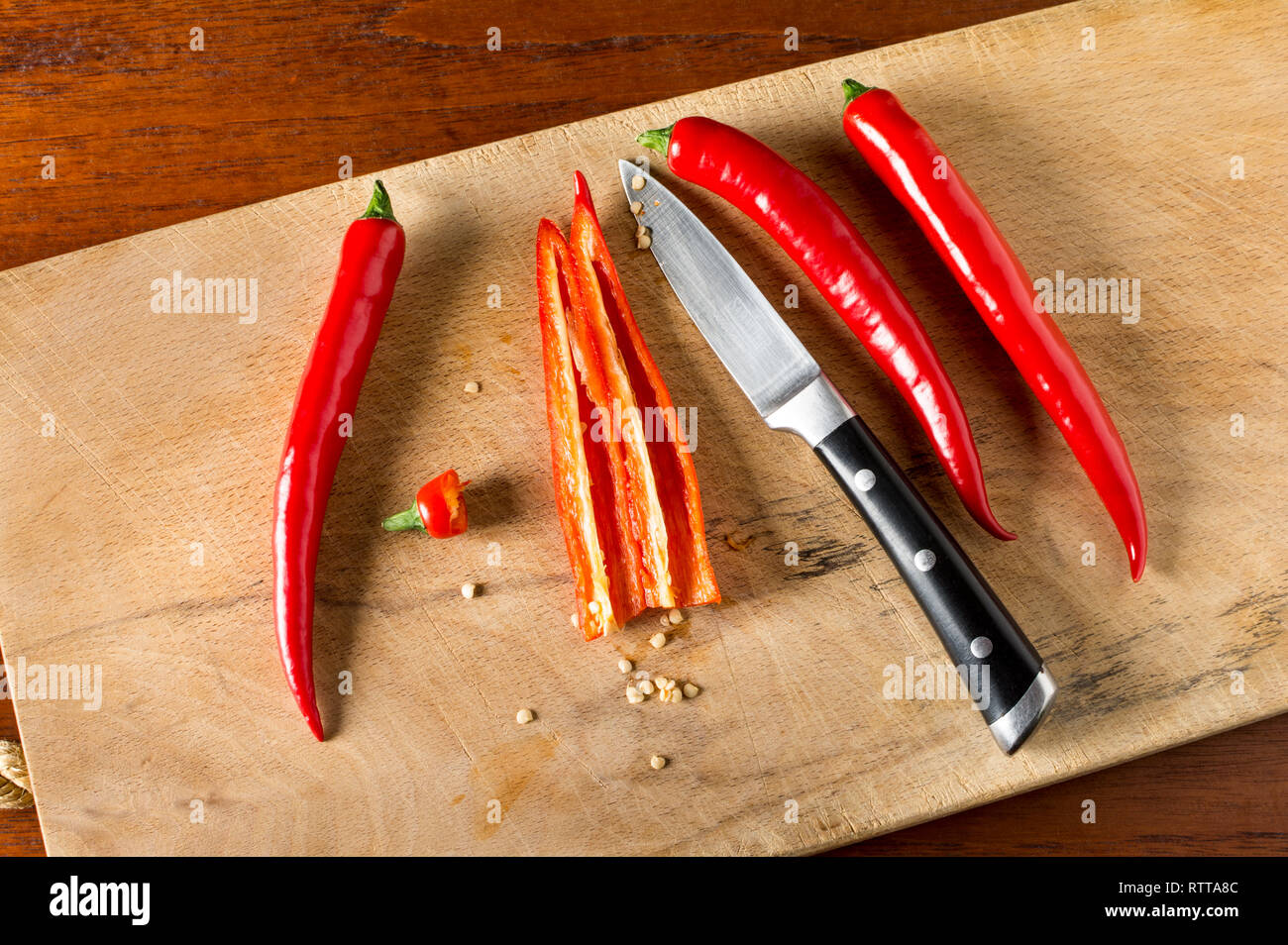 Entkörnen Red Hot Chili Peppers auf einem Schneidebrett mit Messer Stockfoto