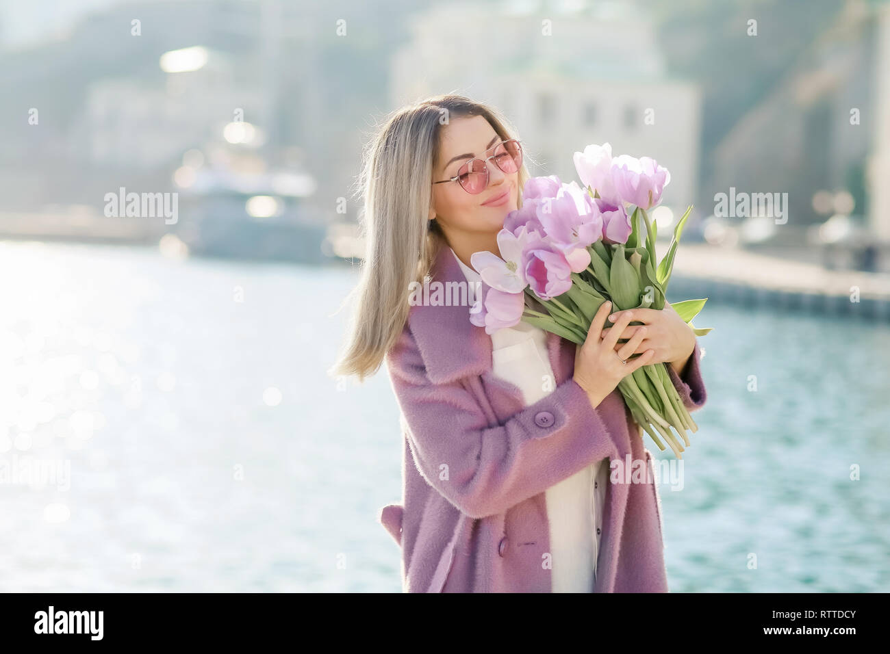 Schöne Frau mit glattes Haar mit einem Bouquet von rosa Tulpen eine Feder sonnigen Tag. Stockfoto