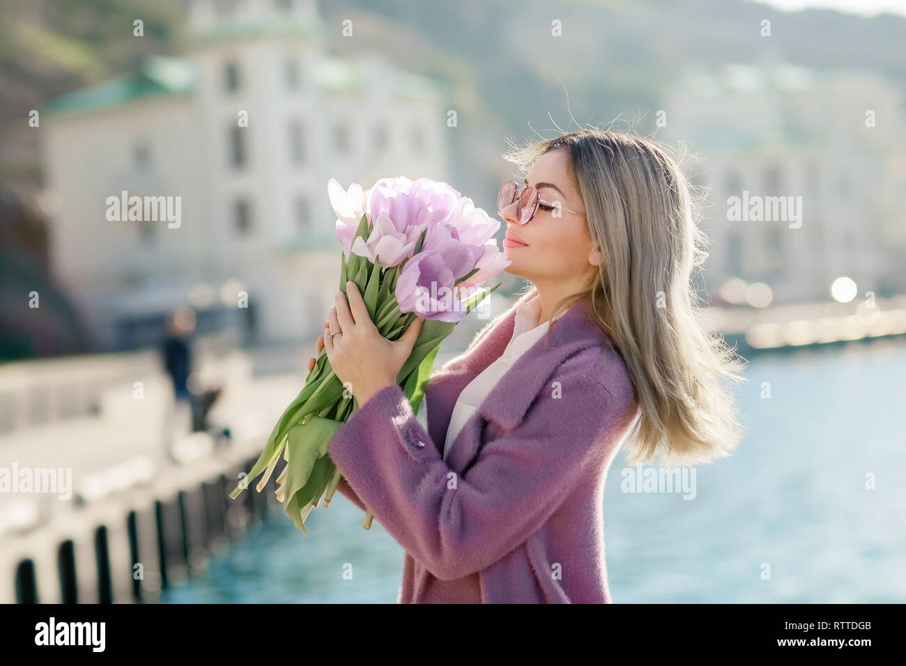 Schöne Frau mit glattes Haar mit einem Bouquet von rosa Tulpen eine Feder sonnigen Tag. Stockfoto