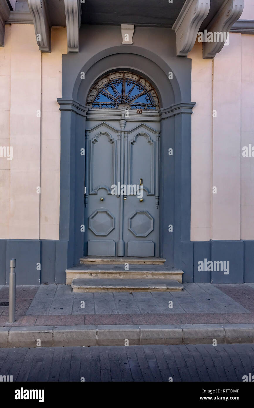 Grand gewölbten Holztür. Traditionelle Einrichtung in zypriotischen Städte gefunden. Grau mit einem blassen rosa Wand gemalt. Stockfoto