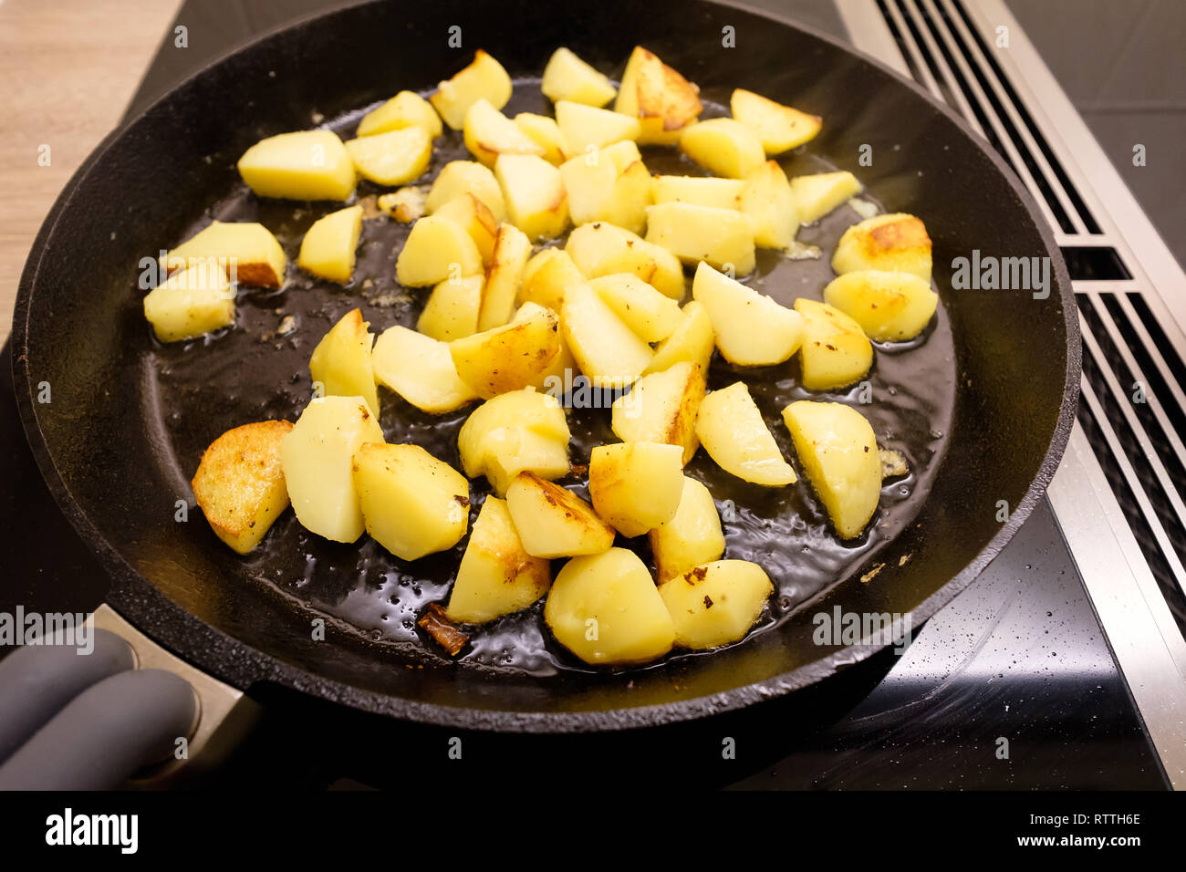 Frittieren von Kartoffeln mit Rauch in einer gusseisernen Pfanne Stockfoto