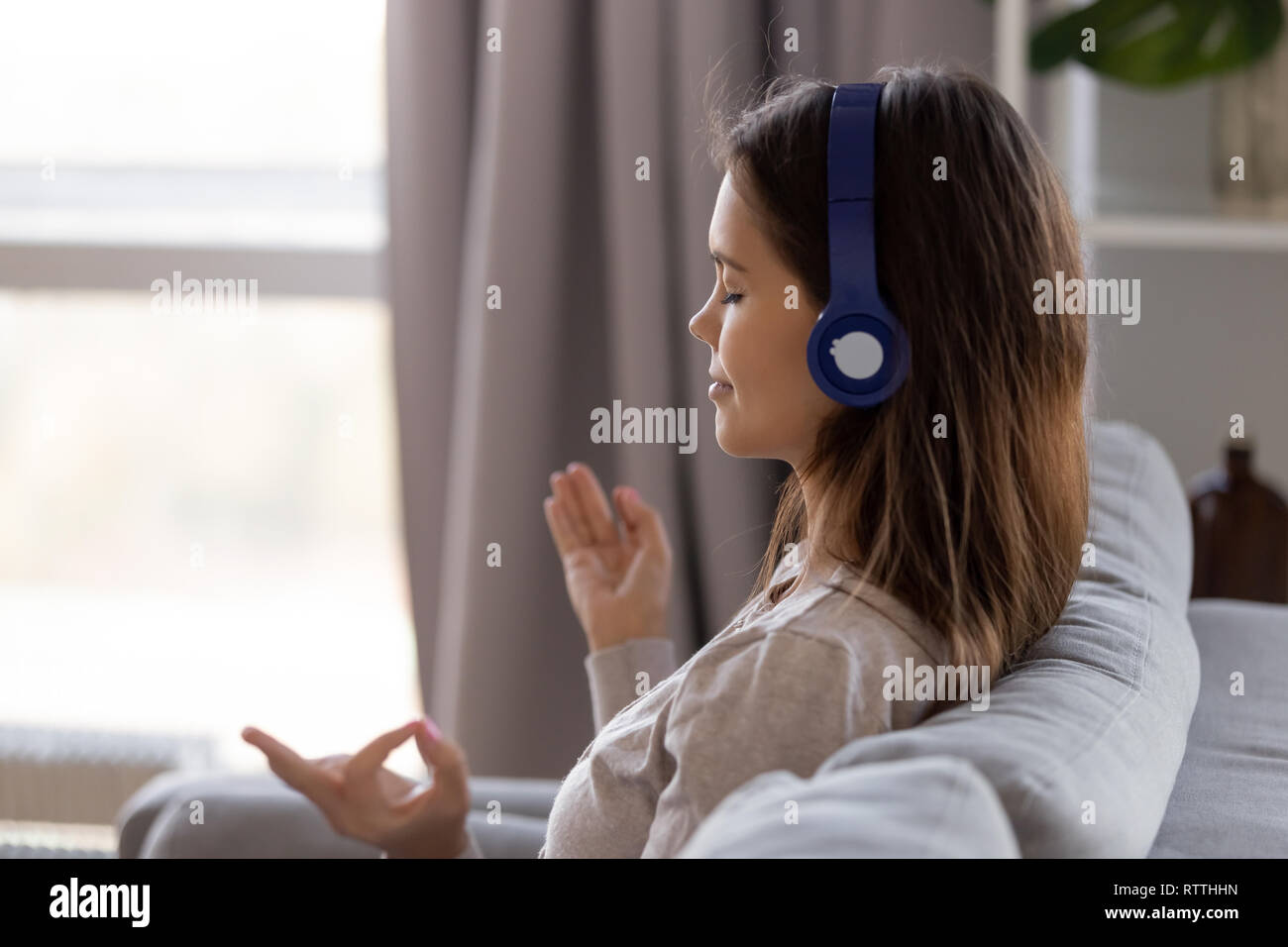Friedliche Frau in Kopfhörer Musik hören und meditieren Stockfoto