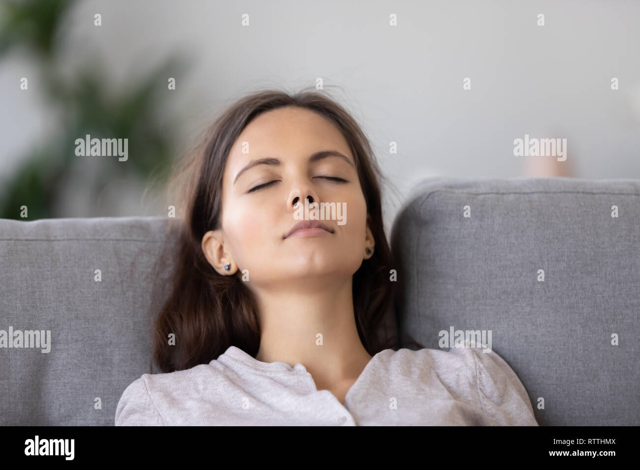 Ruhige junge Frau entspannt auf dem bequemen Sofa mit geschlossen Augen schließen, Stockfoto