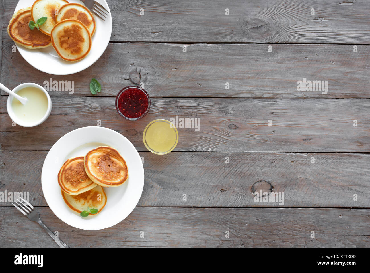 Pfannkuchen zum Frühstück. Hausgemachte Pfannkuchen mit verschiedenen Toppings, Marmelade, Honig - Frühstück für Zwei, Wochenende Familie Frühstück, Ansicht von oben, kopieren. Stockfoto