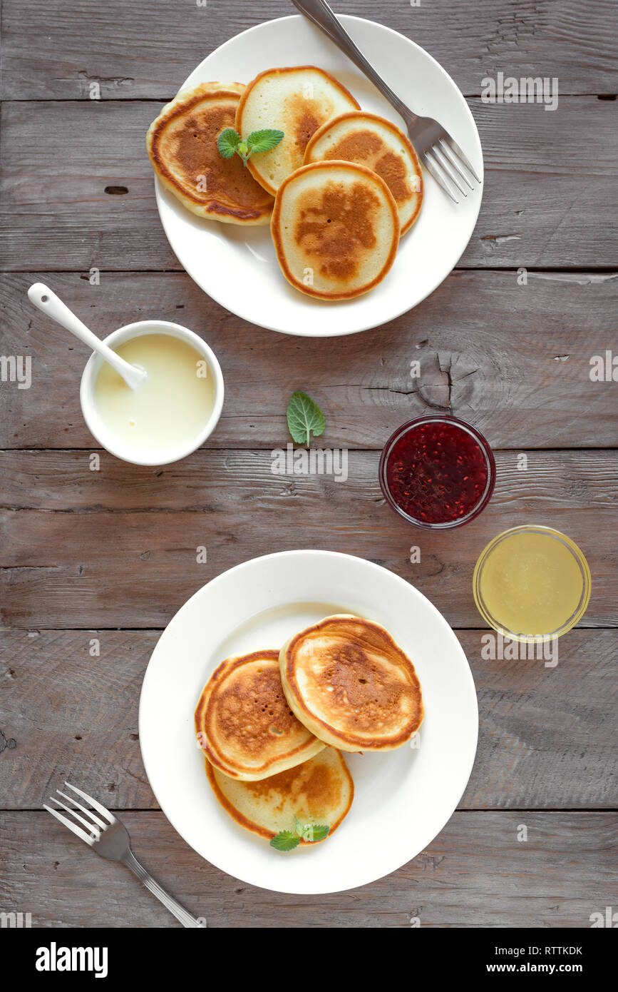 Pfannkuchen zum Frühstück. Hausgemachte Pfannkuchen mit verschiedenen Toppings, Marmelade, Honig - Frühstück für Zwei, Wochenende Familie Frühstück, Ansicht von oben, kopieren. Stockfoto