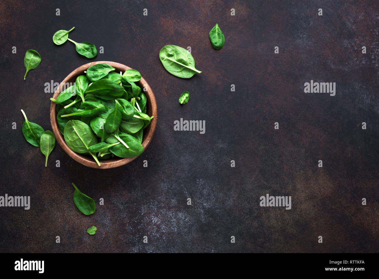 Baby Spinatblätter in der Schüssel auf schwarzem Hintergrund, Ansicht von oben, kopieren. Sauber Essen, Detox, Diät Lebensmittel Zutat - grün Bio Spinat. Stockfoto