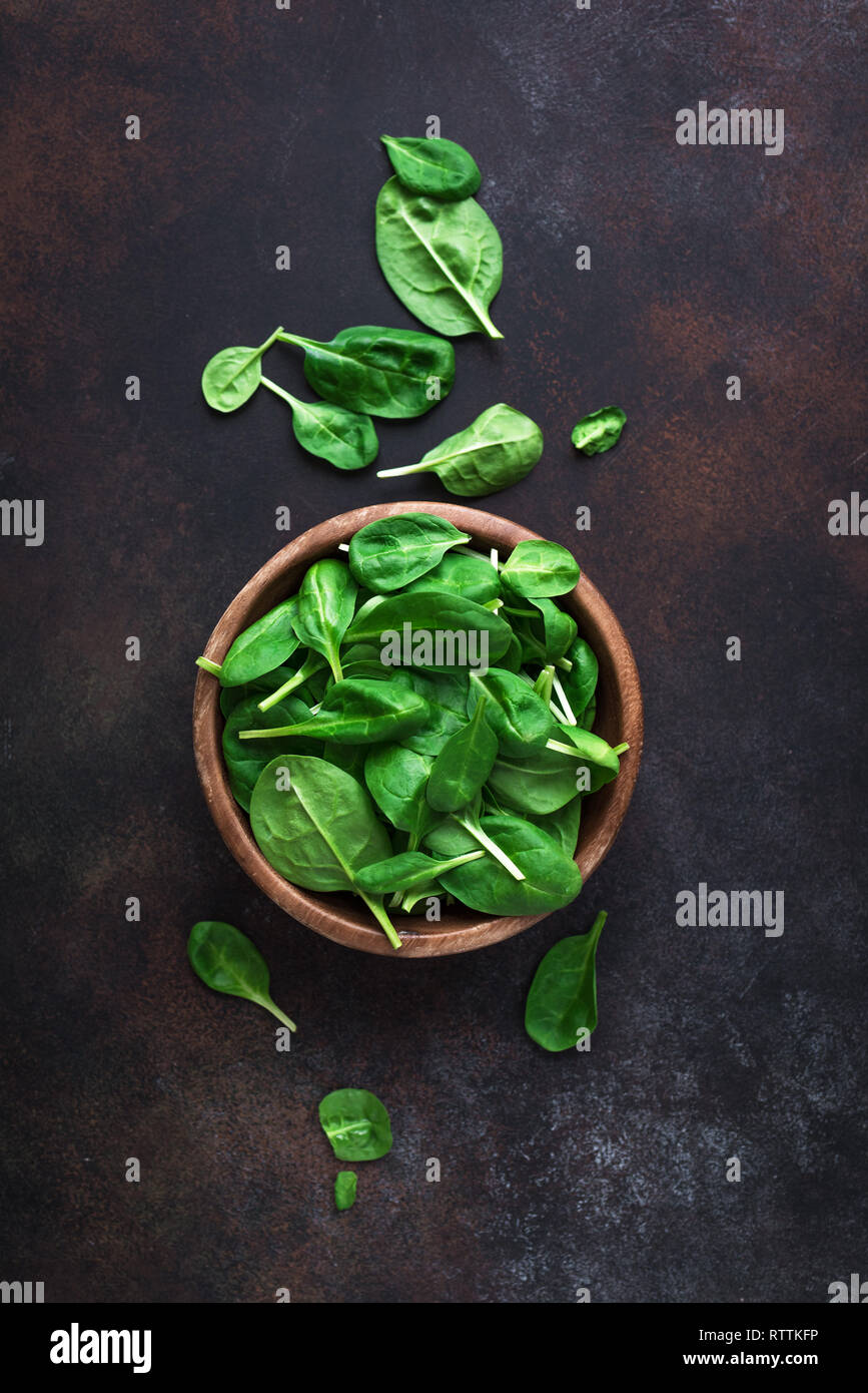 Baby Spinatblätter in der Schüssel auf schwarzem Hintergrund, Ansicht von oben, kopieren. Sauber Essen, Detox, Diät Lebensmittel Zutat - grün Bio Spinat. Stockfoto