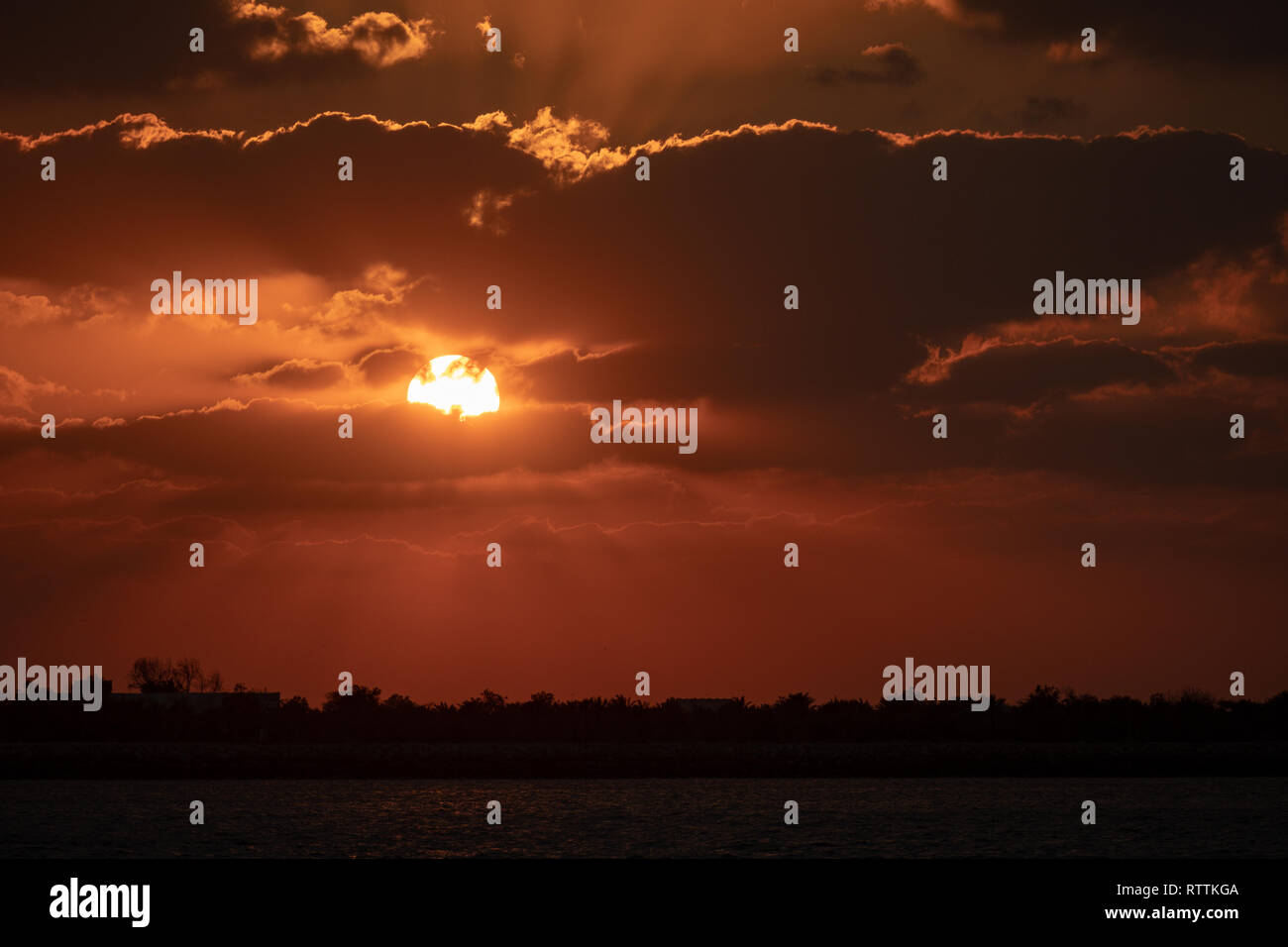 Dramaitc Sonnenuntergang und Sonnenstrahlen durch die Wolken am Strand peaking Stockfoto