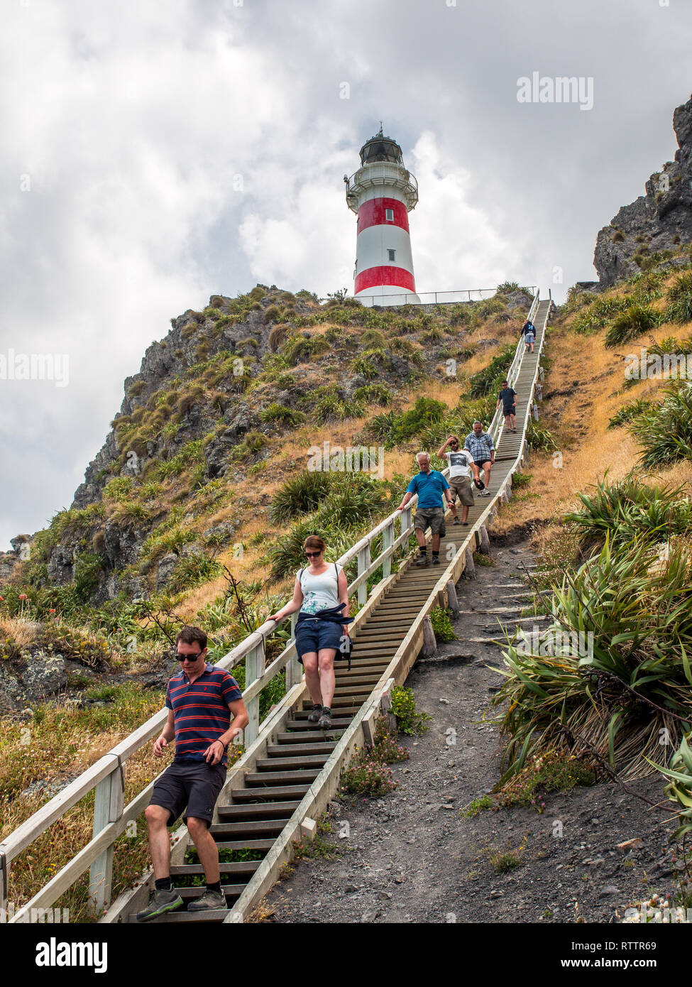 Cape Palliser Leuchtturm, hoch über mehrere Personen, zu Fuß lange Reihe von Schritten auf steilen Hang, Palliser Bay, Wairarapa, Neuseeland Stockfoto