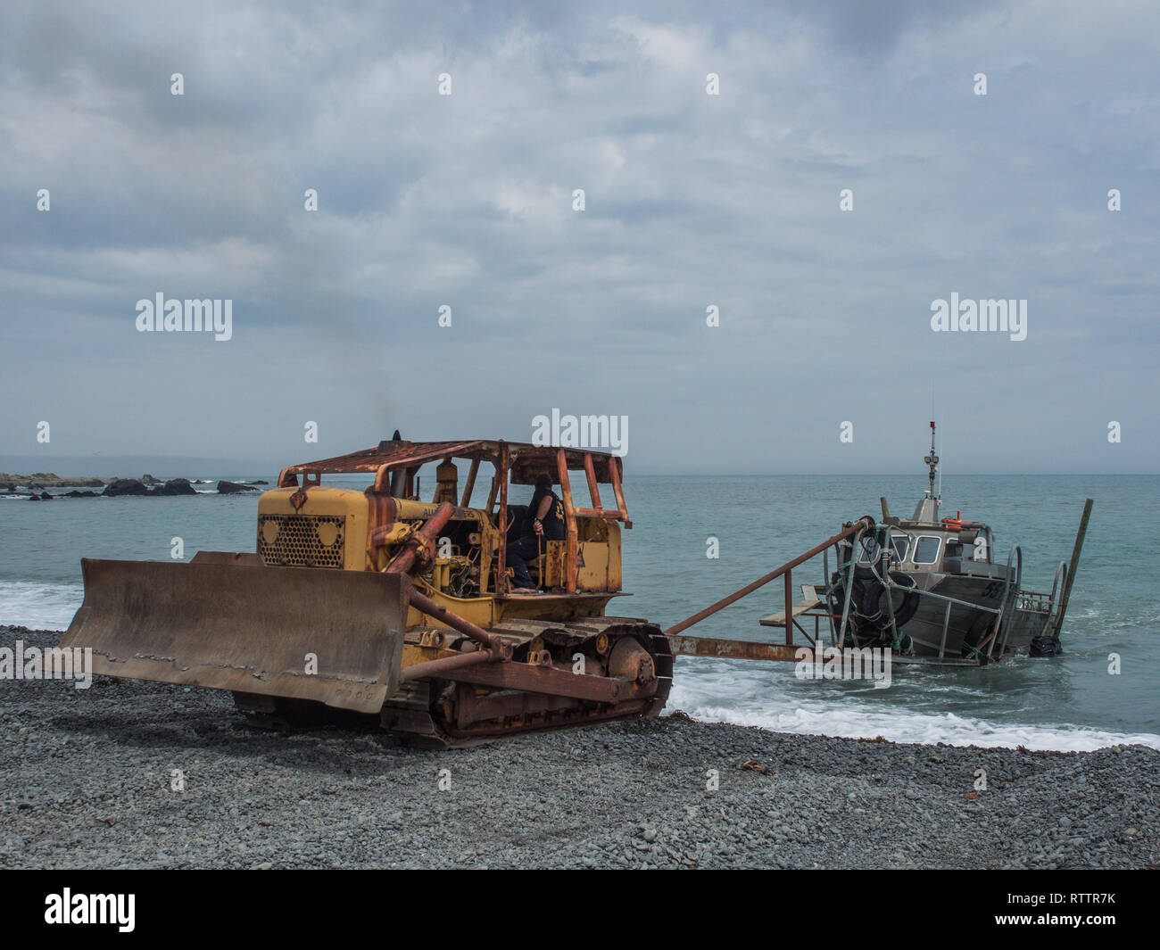 Bulldozer angeln Boot an Land schleppen, Kiesstrand, freiliegenden Küste, Ngawi, Palliser Bay, Wairarapa, Neuseeland Stockfoto