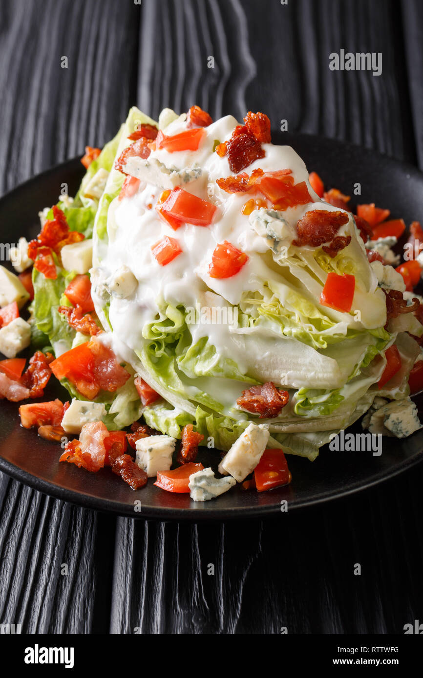 Classic Wedge Salat mit einem Stück Eisbergsalat, Tomaten, roten Zwiebeln, Speck und hausgemachten Blue Cheese Dressing closeup auf einem Teller auf den Tisch. Ver Stockfoto