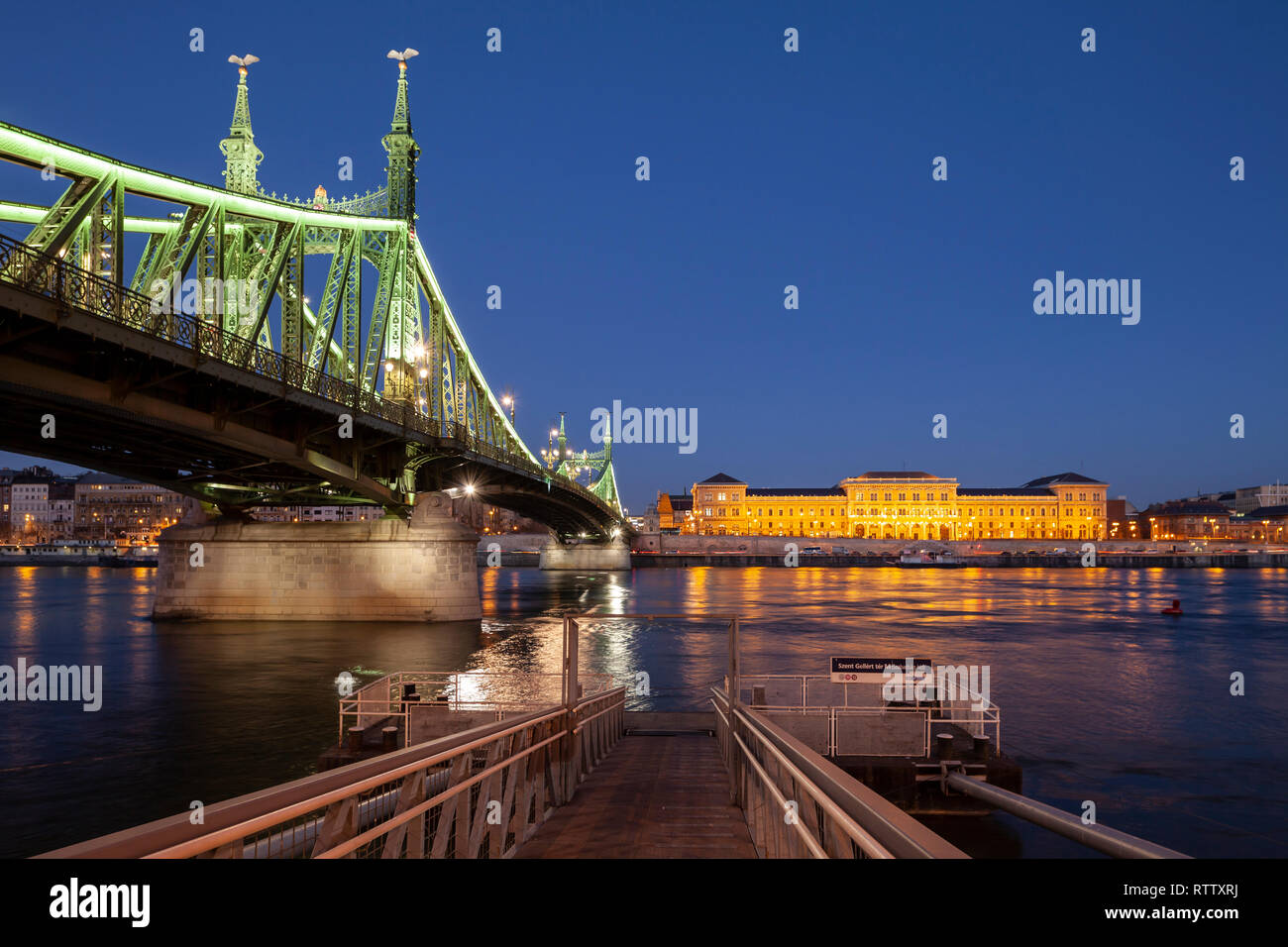 Nacht fällt bei Liberty Bridge und der Corvinus Universität in Budapest, Ungarn. Stockfoto
