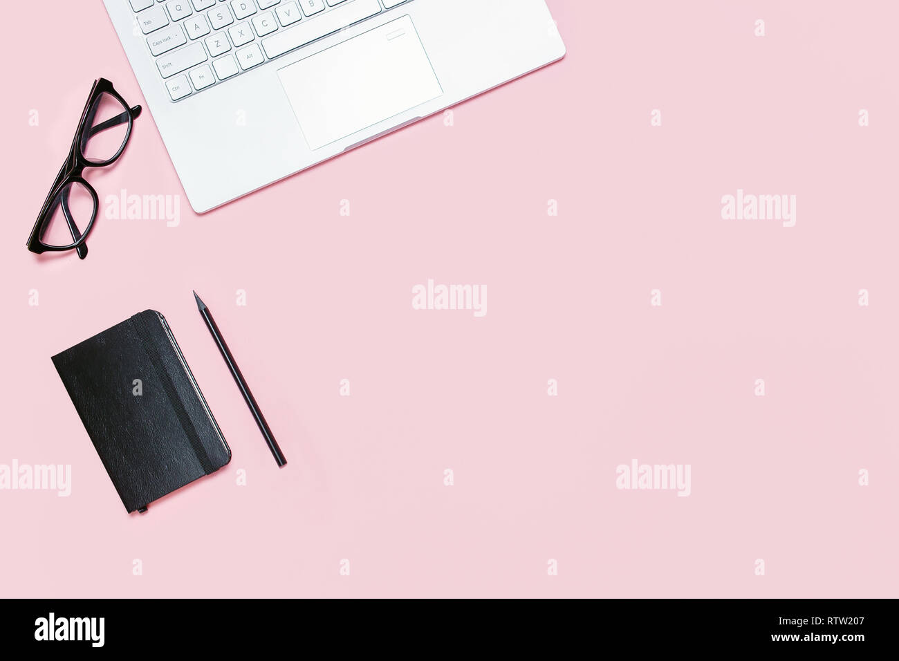 Trendy Pink Tabelle mit Laptop, schwarzer, Brillen, schwarzes Notizbuch und Bleistift. Ansicht von oben. Flach mit Vorlage kopieren. Stockfoto