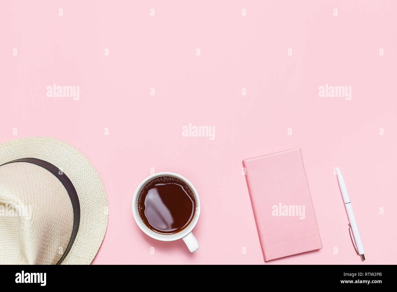 Trendy Pink Tabelle mit Sommer Hut, Tasse Kaffee, rosa Notizbuch und Stift. Ansicht von oben. Flach mit Vorlage kopieren. Stockfoto