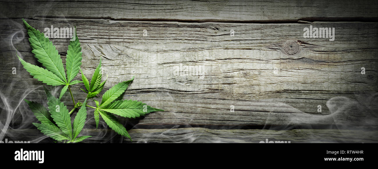 Cannabis Sativa Blätter mit Rauch auf Holztisch - Medizinische rechtliche Marihuana Stockfoto