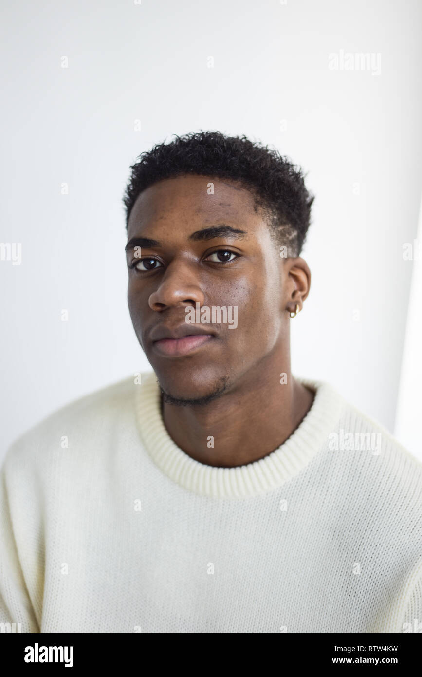Porträt von einem gutaussehenden jungen männlichen Schwarzen isoliert auf einem weißen Hintergrund - Er trägt eine Creme Jumper und sieht nachdenklich/Sad Stockfoto