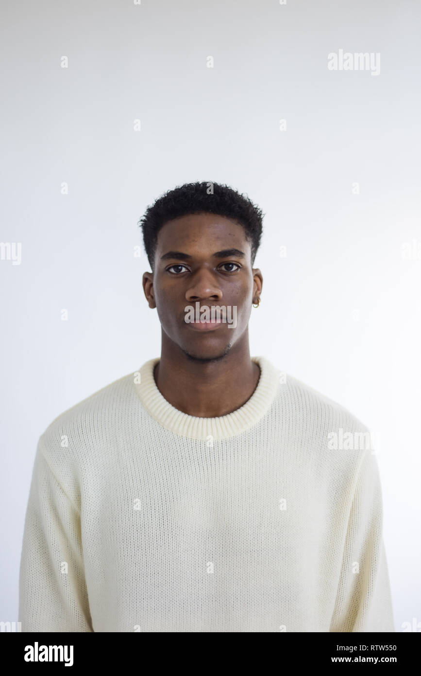 Porträt von einem gutaussehenden jungen männlichen Schwarzen isoliert auf einem weißen Hintergrund - Er trägt eine Creme Jumper und sieht nachdenklich/Sad Stockfoto