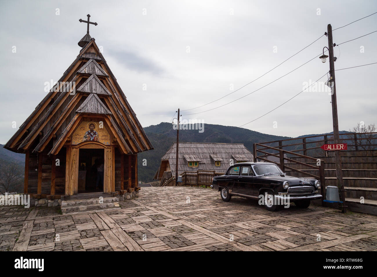 St. Sava Holz- serbisch-orthodoxe Kirche und eine alte Wolga sowjetischen Auto daneben in Drvengrad ethno Dorf gebaut von Emir Kusturica für seinen Film. Serbien Stockfoto