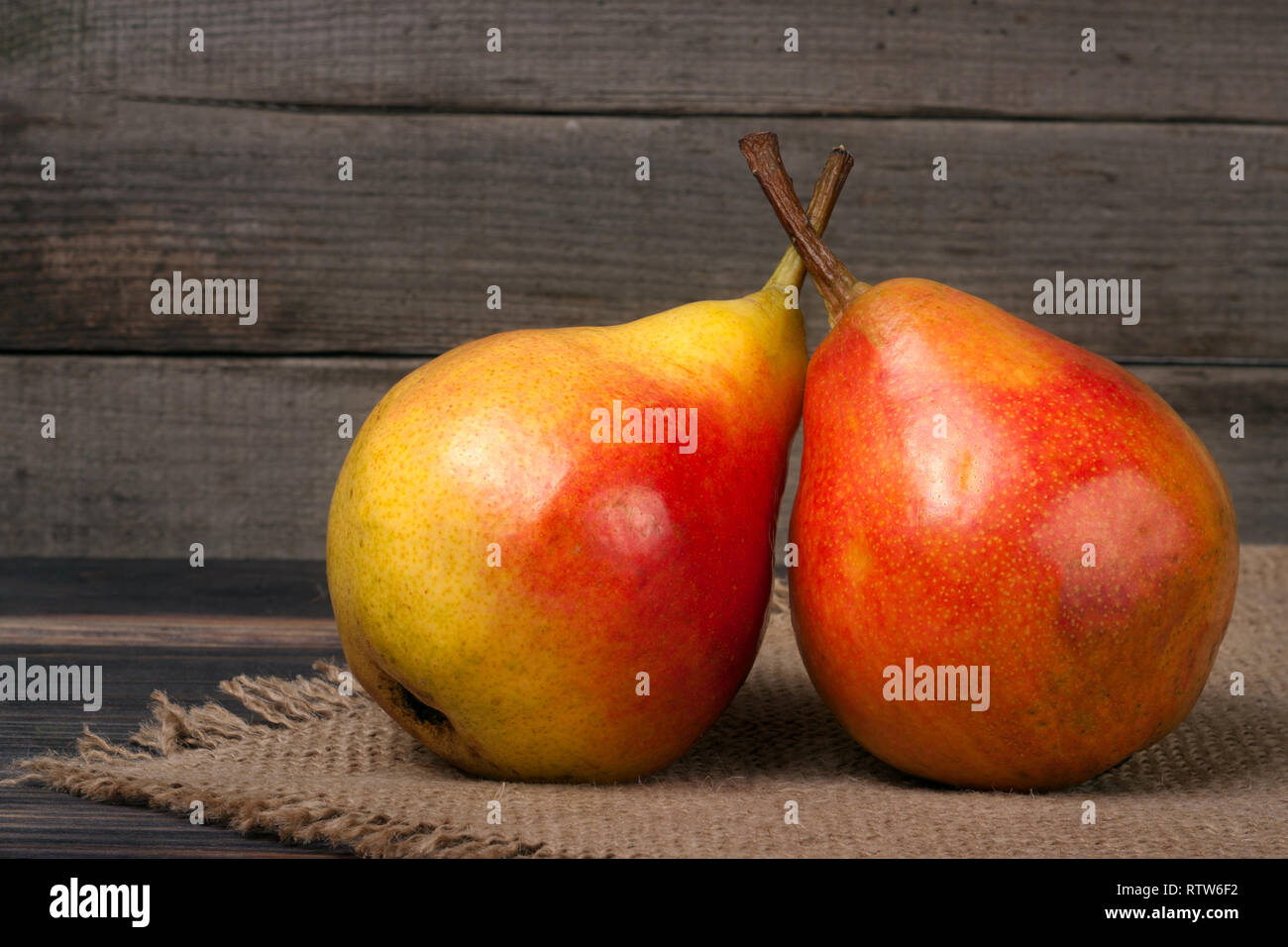 Zwei ganze und halbe der Birne auf einem Holztisch mit Tuch Leinwand Stockfoto