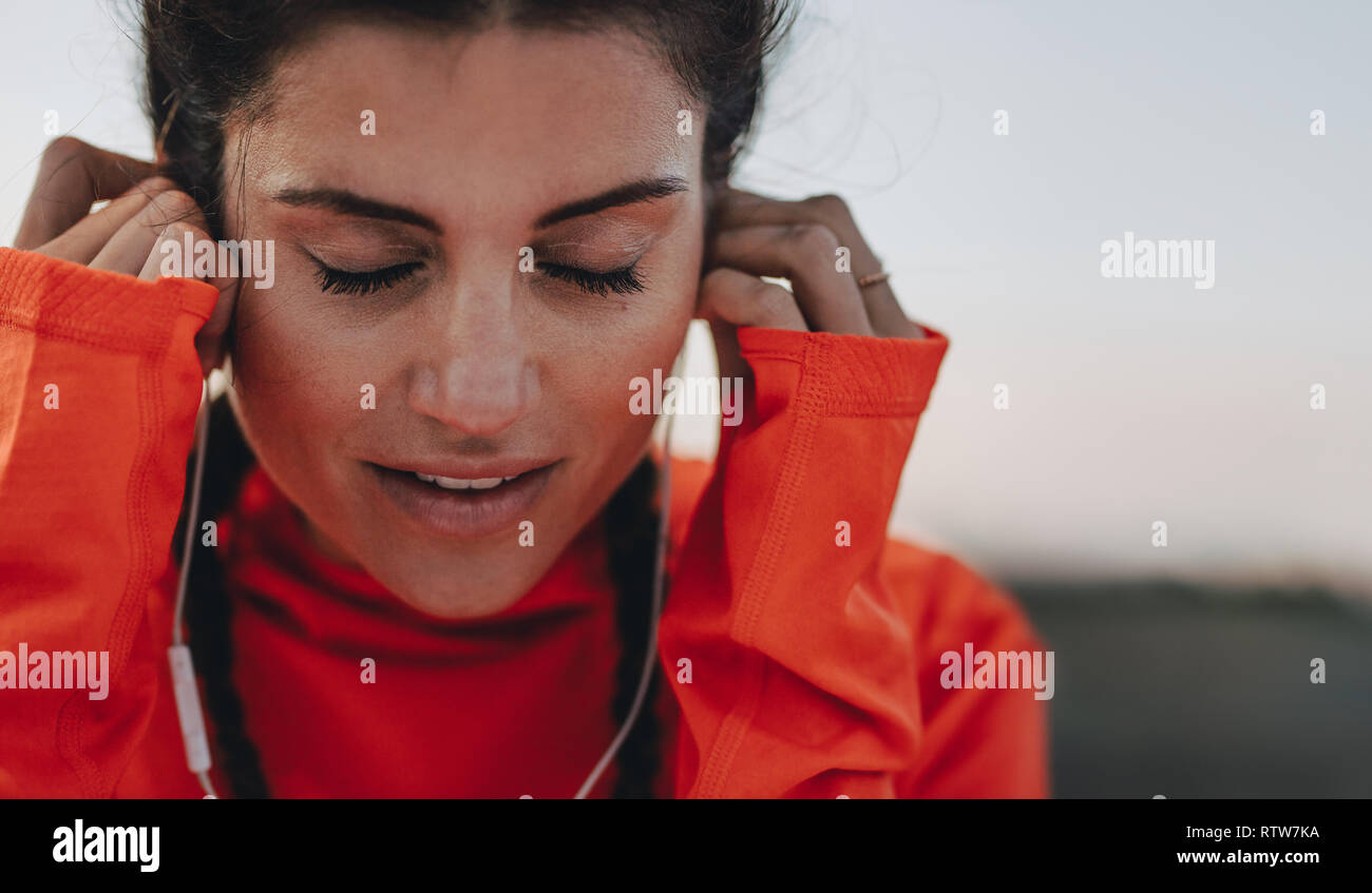 Nahaufnahme von sportlerin einstellen Ihre Ohrhörer während eines Trainings zu brechen. Läuferin Hören von Musik über Kopfhörer während der Pausen im Freien. Stockfoto