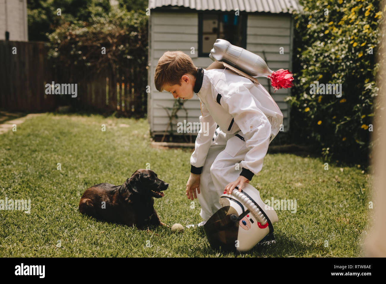 Kleiner Junge im Raumanzug spielen im Freien mit seinem Hund. Kid vorgibt, ein Astronaut verbringt Zeit mit seinen Hund zu sein. Stockfoto