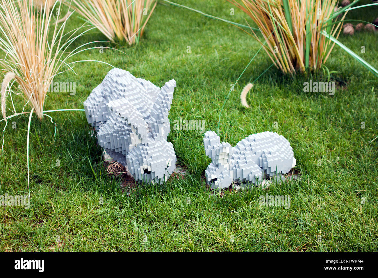 Spielzeug Grau Ziegelstein Kaninchen Familie Essen im Rasen, Essen das Gras bei gutem Wetter. Stockfoto