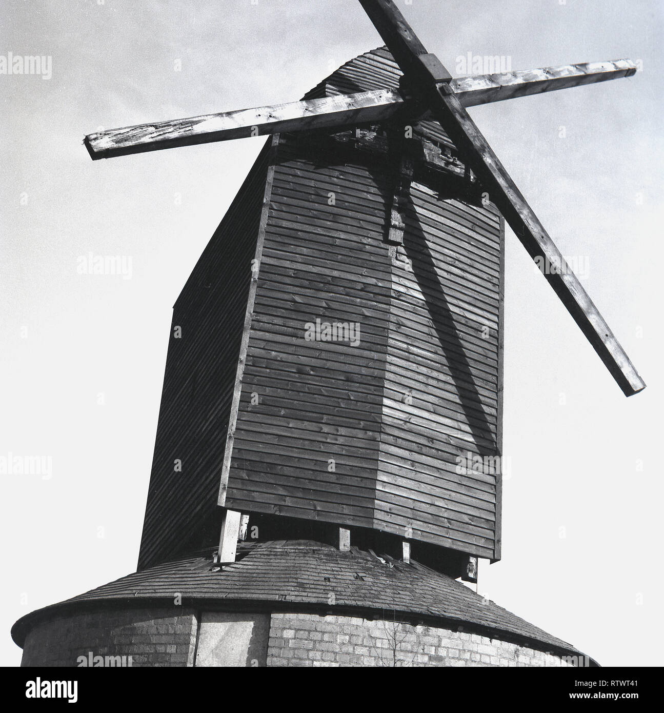 1970er Jahre, den Brill Mühle, Bucks, England. Ein traditionelles Mühle, das Bild zeigt die Ebene, Basic' post Mill' hier mit hölzernen Flügeln oder Blades und eine hölzerne Klappe 'post' auf die Struktur der Mühle oder Körper fixiert. Diese Art von "post Mill' gilt als die früheste Art der Europäischen Windmühle und wird so genannt, da die großen Pfosten ist auf die Struktur oder trestle umgeben, wie hier durch einen roundhouse gesehen das Gestell von der Witterung zu schützen und um Speicherplatz ausgeglichen. Stockfoto