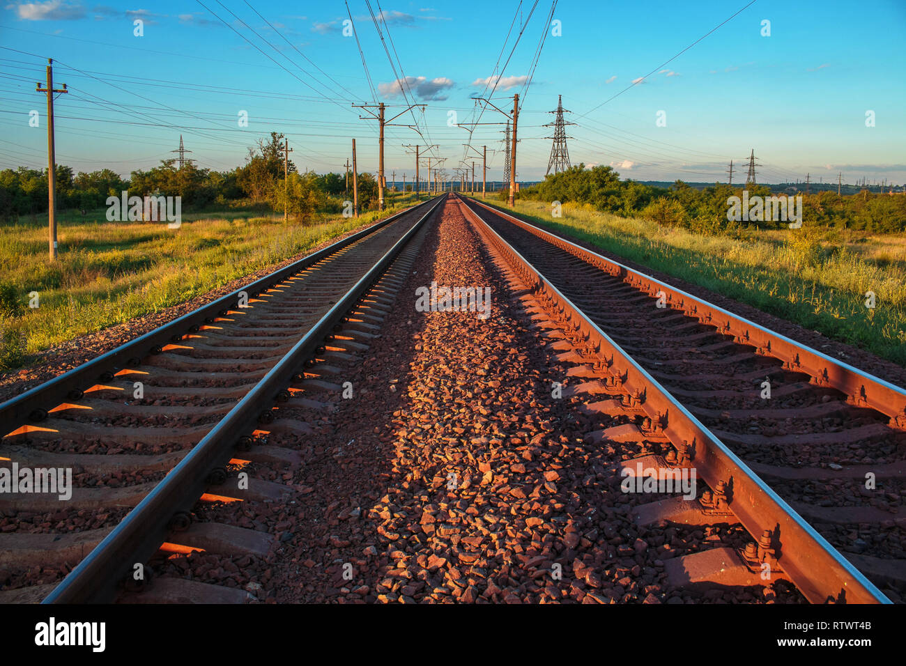 Eine doppelte endlose Eisenbahn. Unendliche Eisenbahn führenden unendlich ist. Ein Sonnenuntergang Landschaft. Kriviy Rih, Ukraine. Sommer Eisenbahn Landschaft Stockfoto