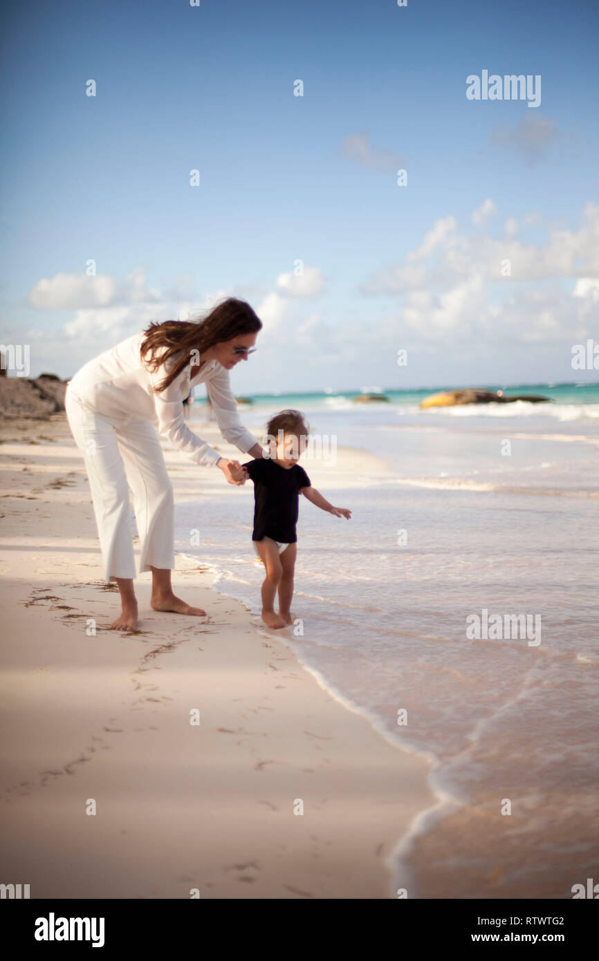 Auf Sonnenuntergang Strand Mutter und Baby erforscht das Meer Stockfoto