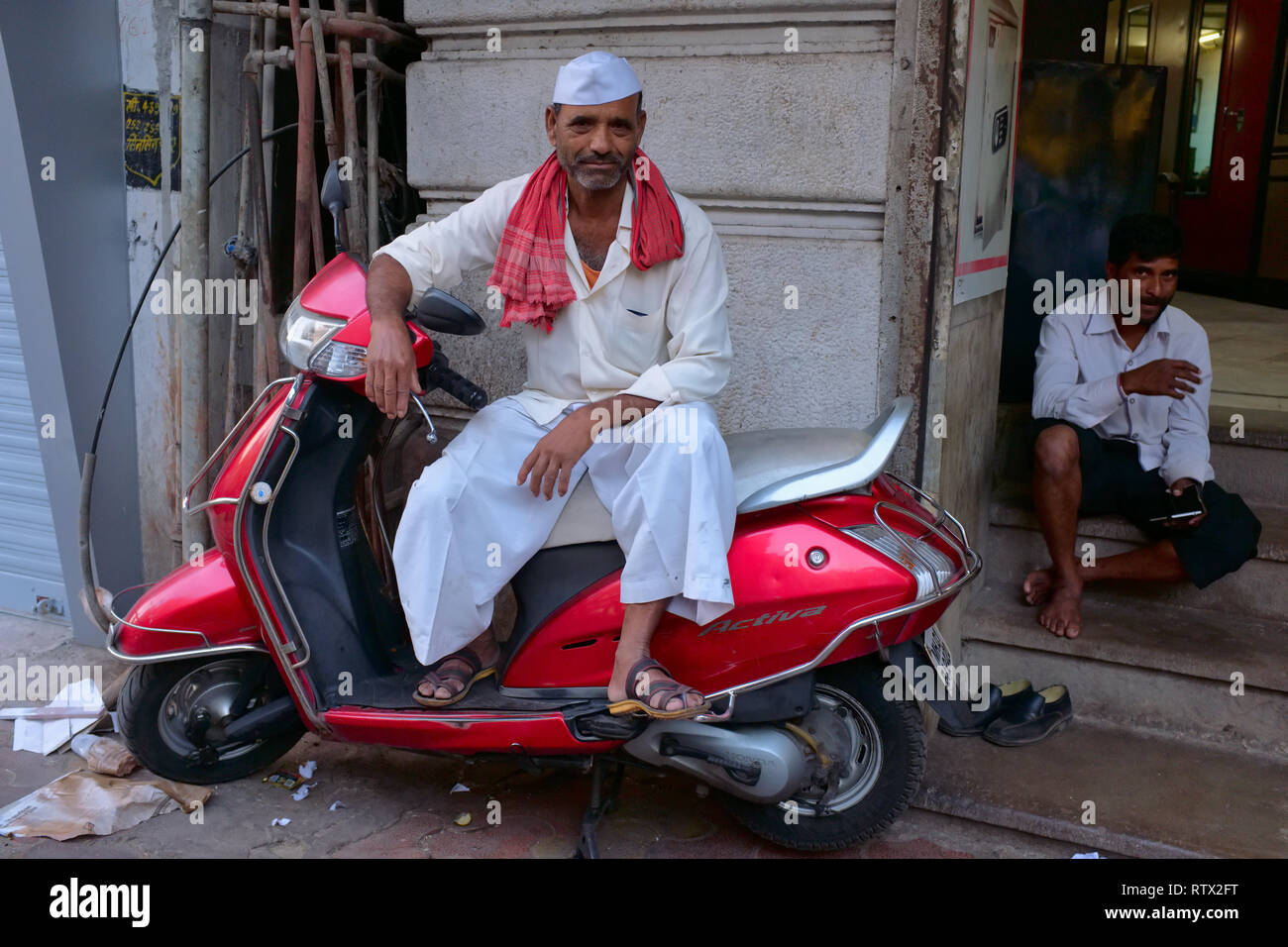 Einen Handkarren Abzieher in Kalbadevi Road, Mumbai, Indien, einer ethnischen Maharashtrian, ruht auf einem Motorroller, seine Farbe zufällig seinen Schal passenden Stockfoto