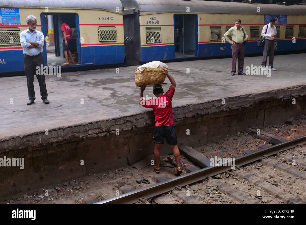 Ein Portier an Chhatrapati Shivaji Maharaj Terminus, der verkehrsreichste Bahnhof in Mumbai, Indien, gefährliche Kreuzung einer Bahnstrecke für eine Verknüpfung Stockfoto