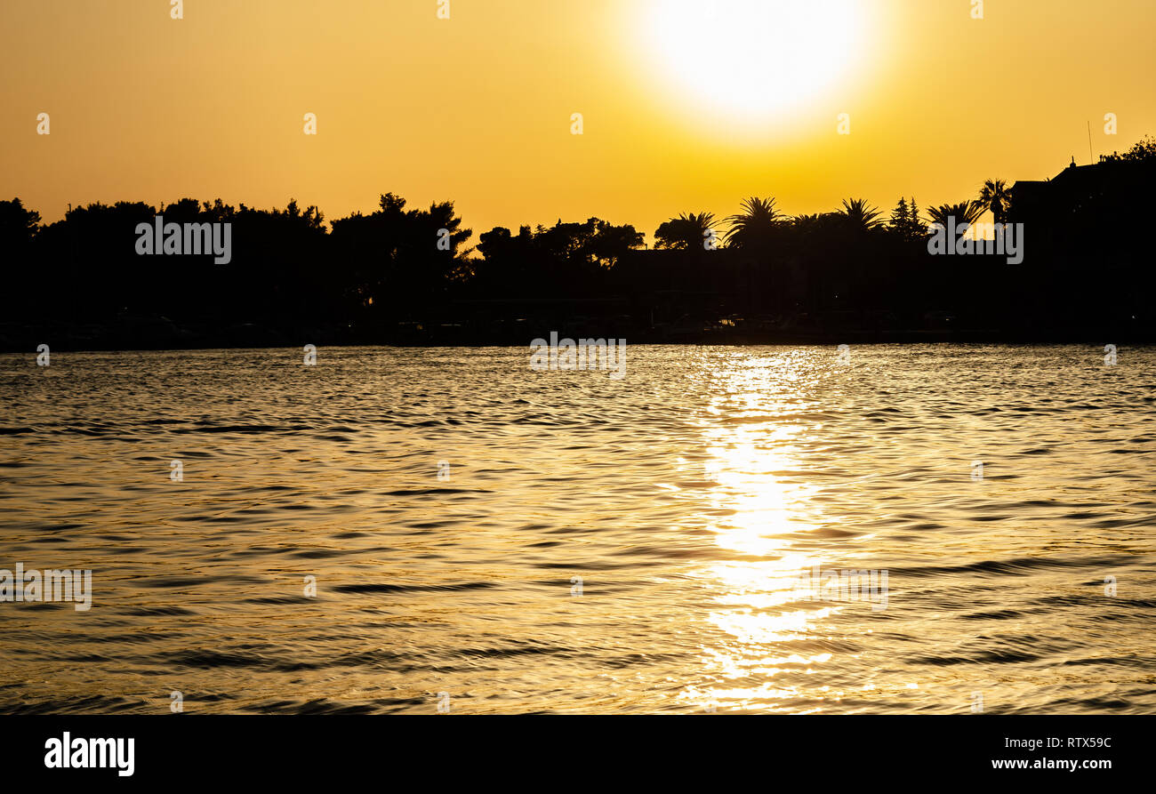 Silhouette der Ufer mit Bäumen im Meer bei Sonnenuntergang. Stockfoto