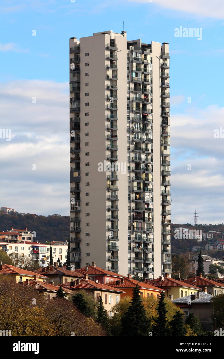 Einzigen hohen Wolkenkratzer ragen Mehrfamilienhäusern und kleineren Gebäuden an der Seite des Hügel mit bewölktem blauen Himmel im Hintergrund umgeben Stockfoto