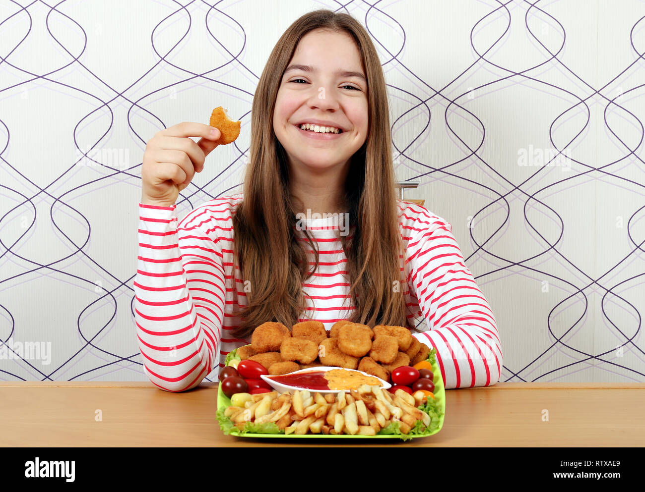 Happy Teenager mit leckeren Chicken Nuggets und Pommes Frites Stockfoto