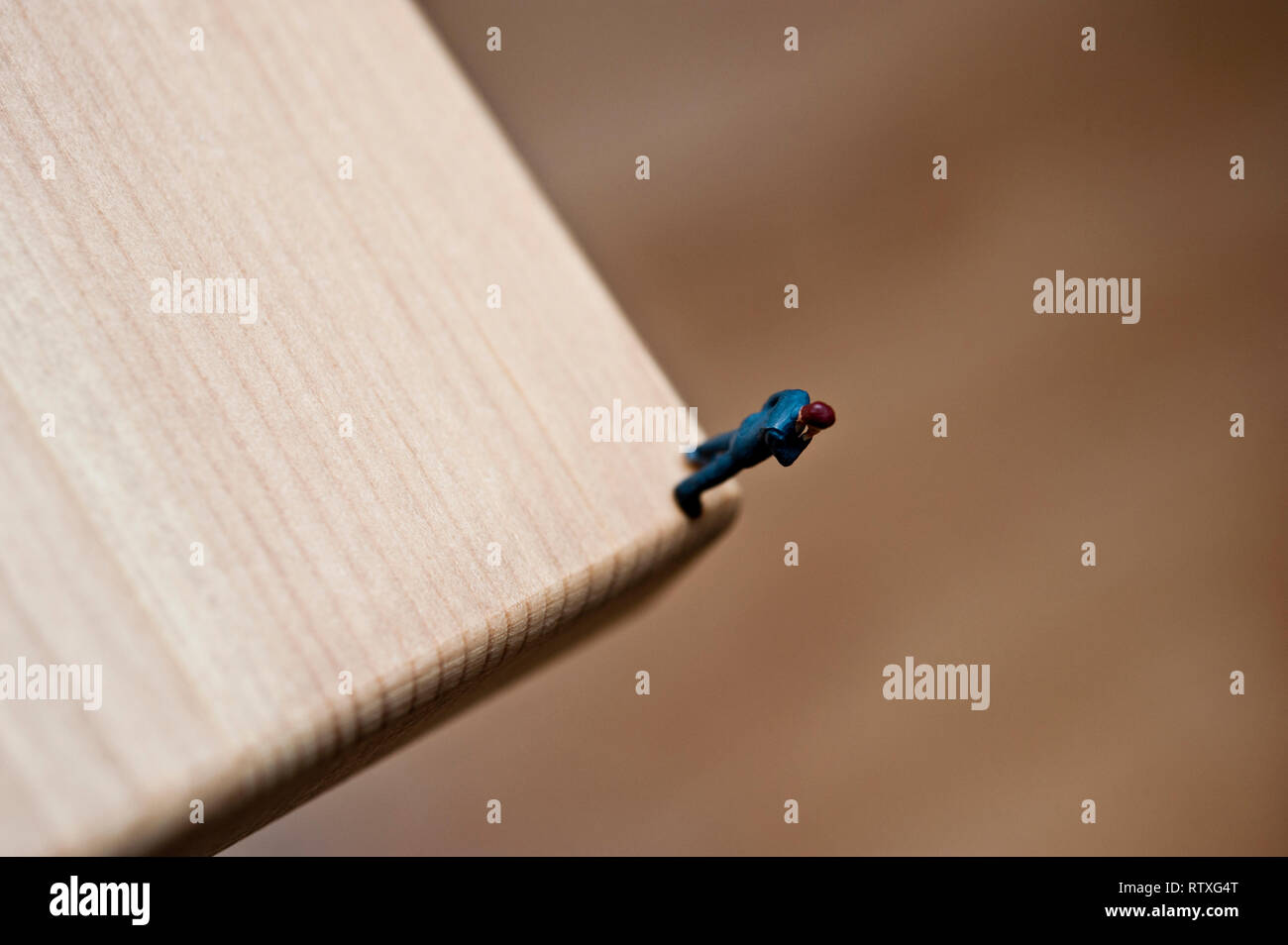 Miniatur Figur an der Ecke einer Tabelle, Konzept für den Menschen auf der Kante Stockfoto