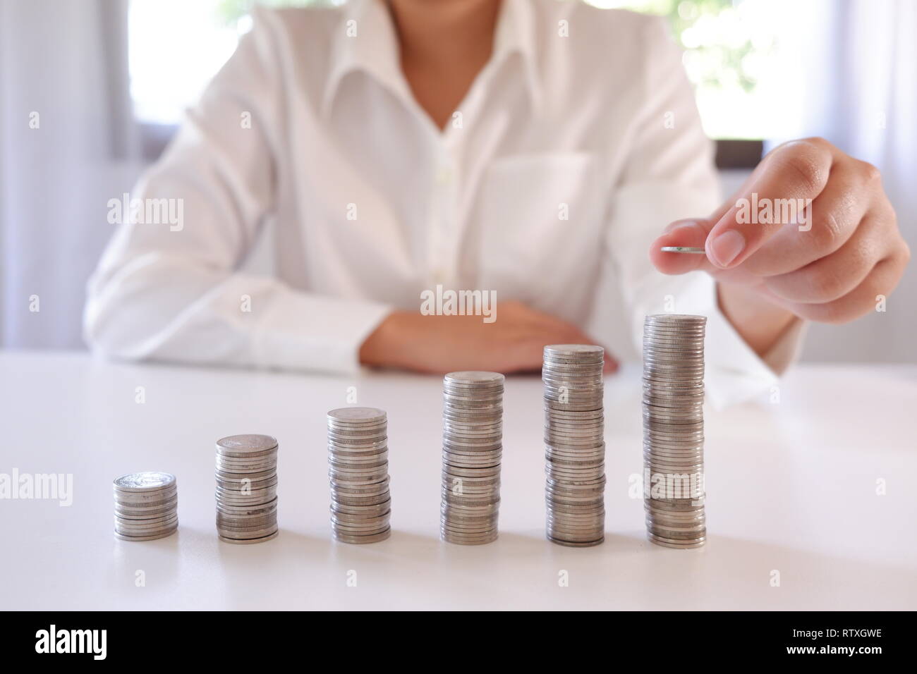 Business Person, Münze über die zunehmende Münzen Stapeln. Stockfoto