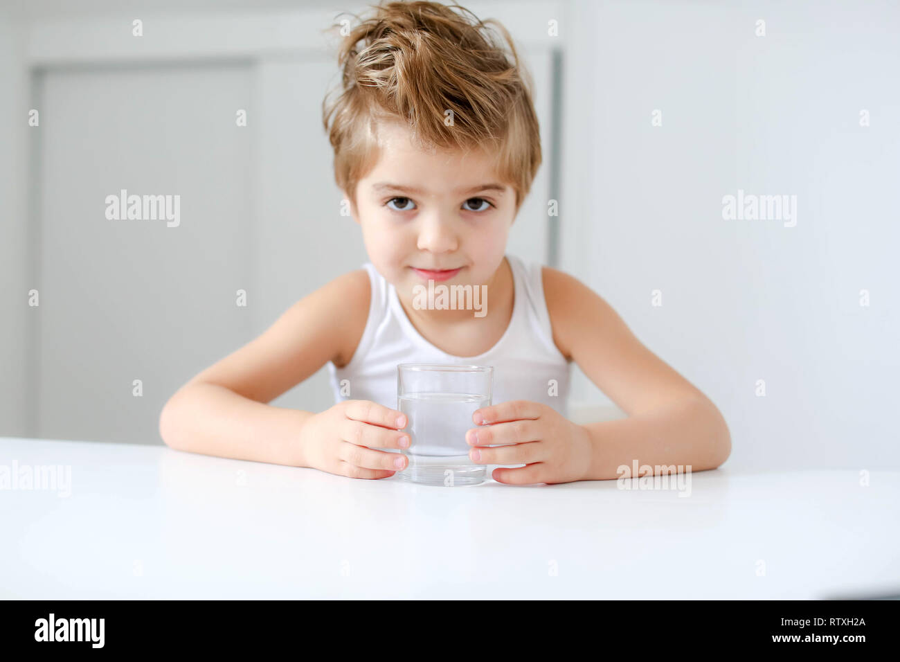 Nett lächelnden Jungen mit Glas Wasser auf einem weißen Hintergrund. Stockfoto