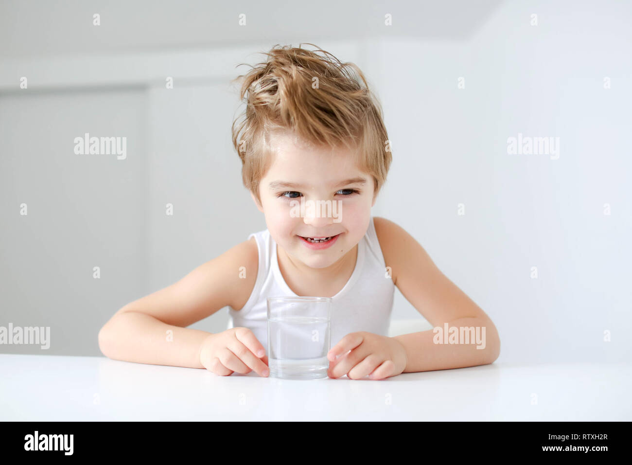 Nett lächelnden Jungen mit Glas Wasser auf einem weißen Hintergrund. Stockfoto