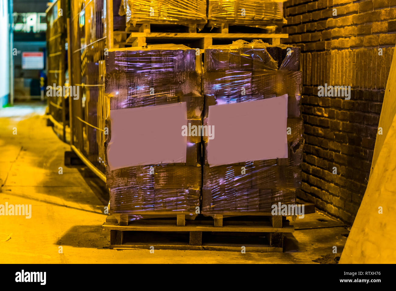 Palette mit blanko Etiketten vor eine große Reihe von gestapelten Paletten, Palette mit Steinpflaster gefüllt, Bauindustrie und logistischen Hintergrund Stockfoto