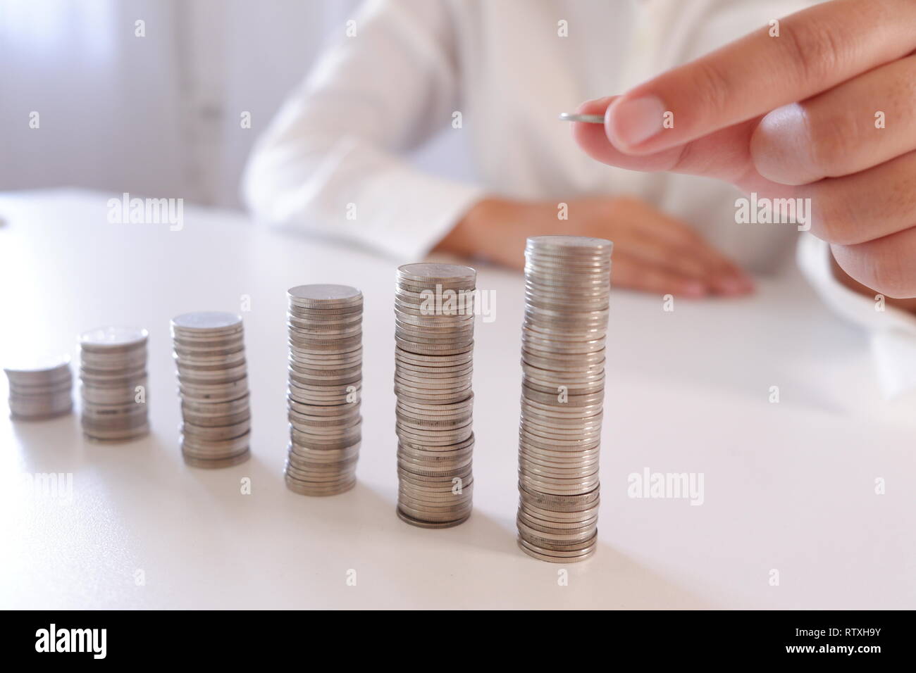 Business Person, Münze über die zunehmende Münzen Stapeln. Stockfoto