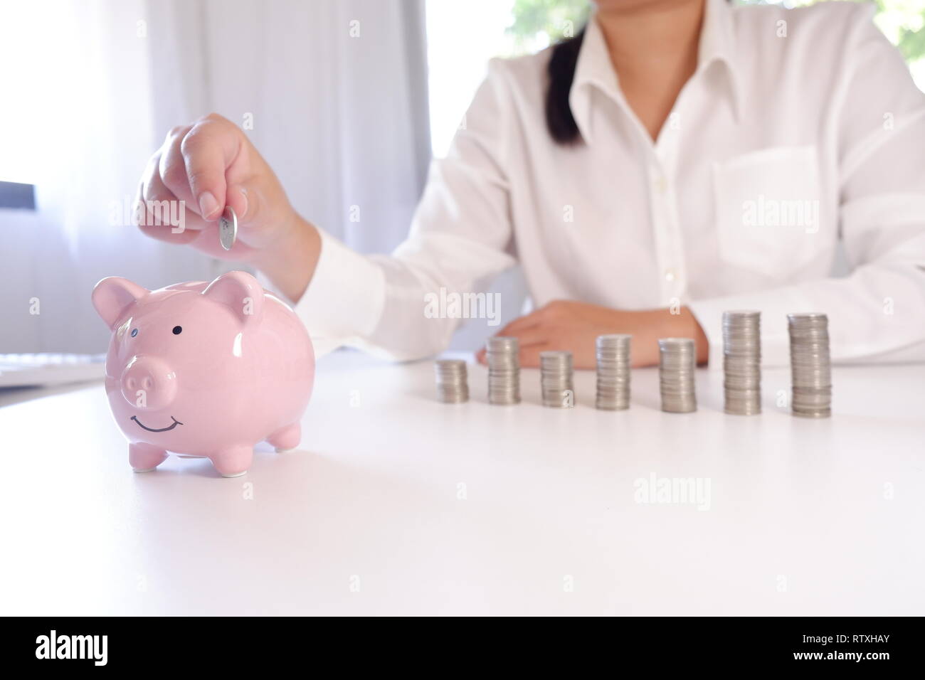 Unternehmer Münzeinwurf Sparschwein mit Stapel von Münzen über den Schreibtisch Stockfoto