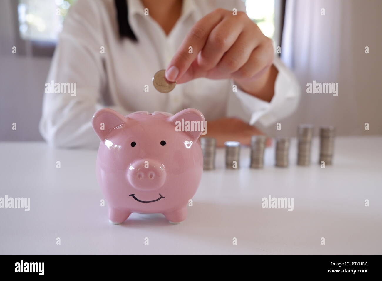 Unternehmer Münzeinwurf Sparschwein mit Stapel von Münzen über den Schreibtisch Stockfoto