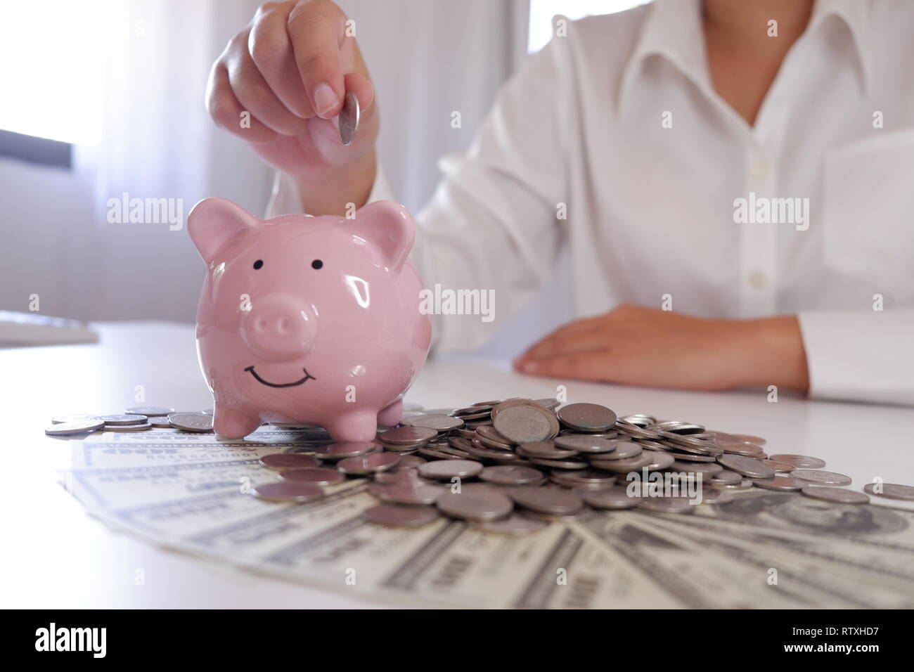 Menschen einfügen Münze in Sparschwein mit Münzen und Geld über den Schreibtisch Stockfoto