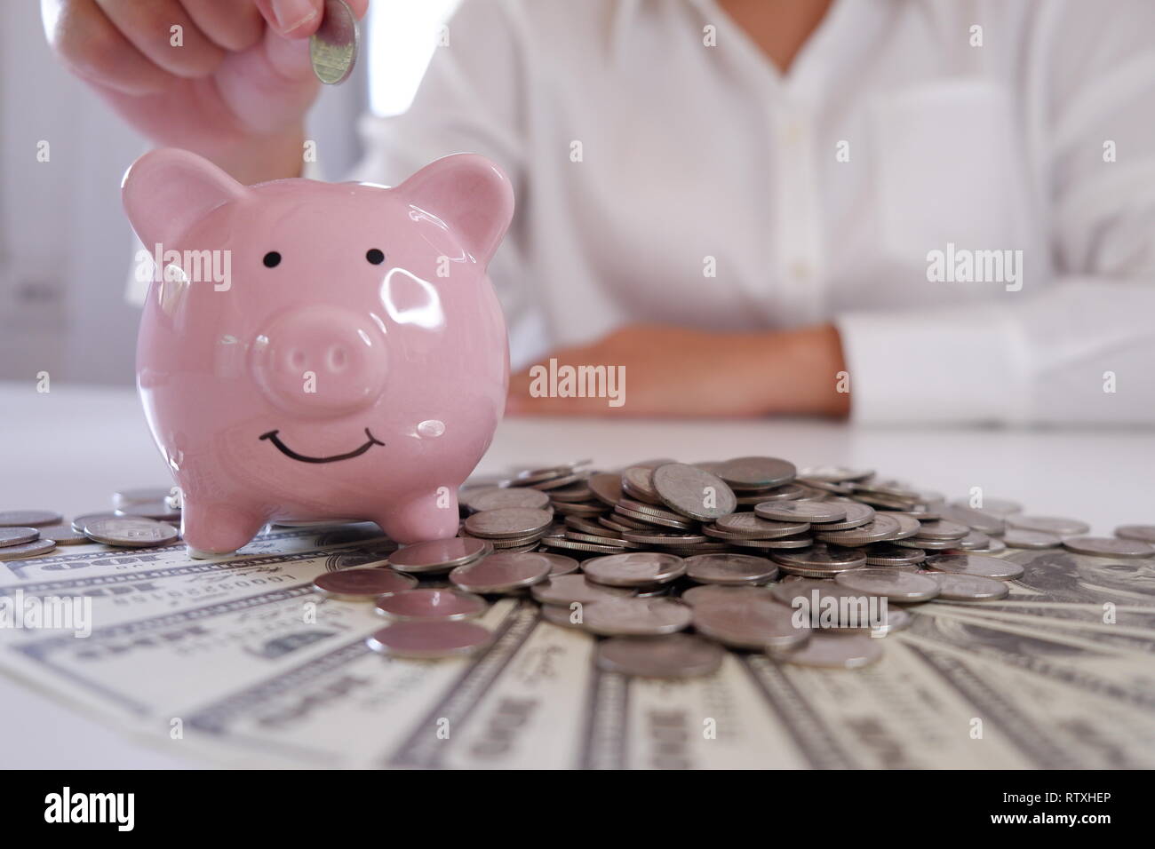 Menschen einfügen Münze in Sparschwein mit Münzen und Geld über den Schreibtisch Stockfoto