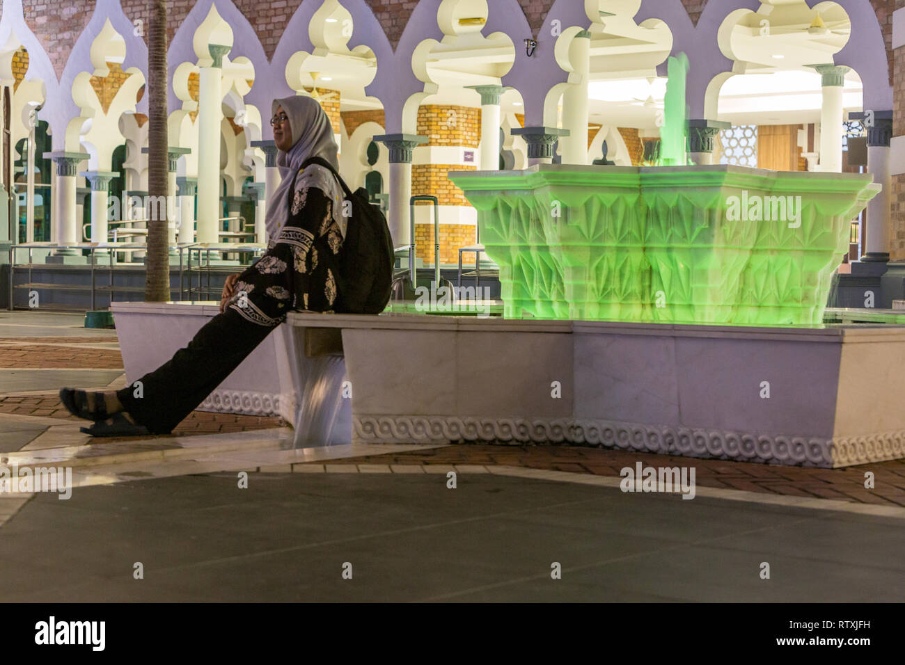 Frau lehnte sich gegen Brunnen, Masjid Jamek (Jamek Moschee), Kuala Lumpur, Malaysia. Stockfoto
