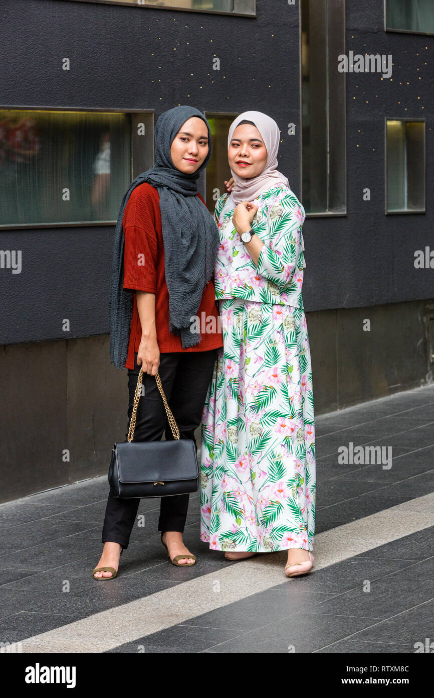 Junge Malaysische Frauen für ein Foto, traditionelles Kleid vs Casual im westlichen Stil, Pavilion Mall, Bukit Bintang, Kuala Lumpur, Malaysia posieren. Stockfoto