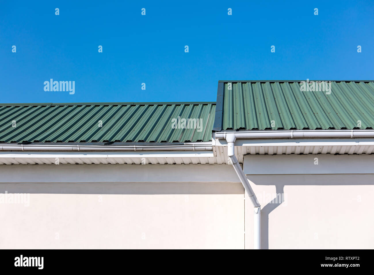 Grün auf dem Dach des neu erbauten Haus und White Metal Dachrinne Rohre und abflußrohr auf blauen Himmel Hintergrund Stockfoto